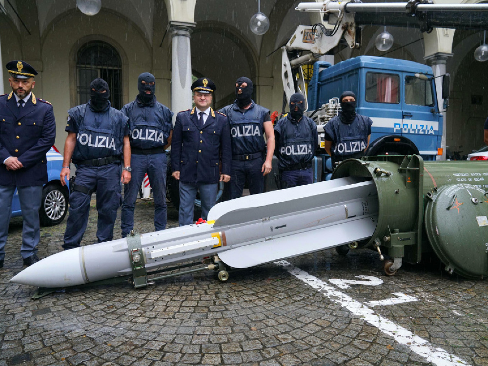 Príslušníci talianskej jednotky talianskej polície stoja pri zhabanej rakete vzduch - vzduch od francúzskej spoločnosti Matra z výzbroje katarskej armády z hangáru na letisku v Pavii v severnom Taliansku 