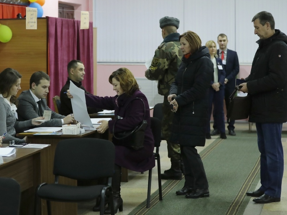 Bieloruskí voliči dostávajú hlasovacie lístky počas hlasovania v parlamentných voľbách vo volebnej miestnosti v Minsku