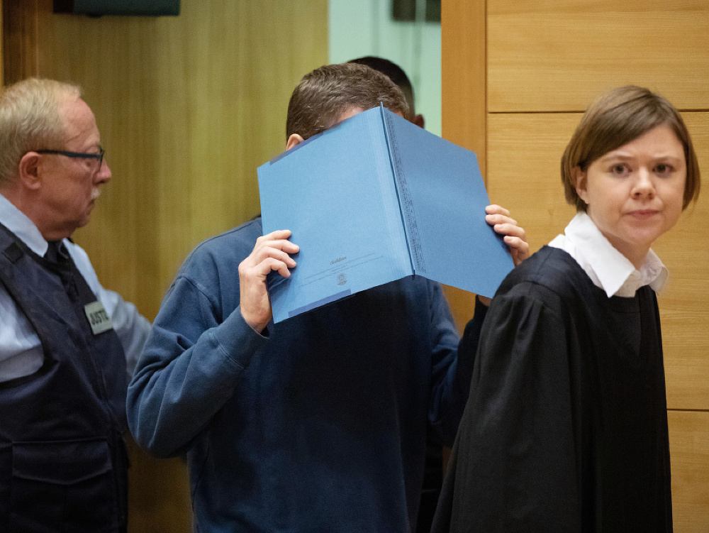 Na archívnej snímke z 15. novembra 2018 obžalovaný muž si zakrýva tvár počas príchodu na súdne pojednávanie v Bielefelde.
