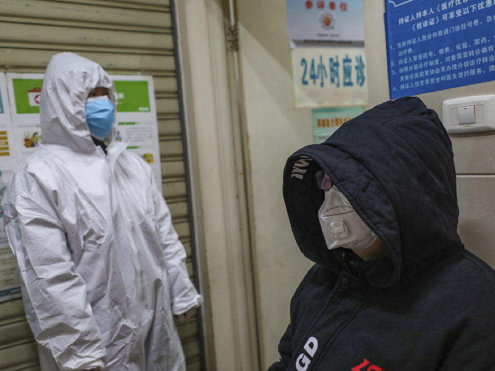 Cestujúci majú na tvári ochranné rúška pred železničnou stanicou v Pekingu
