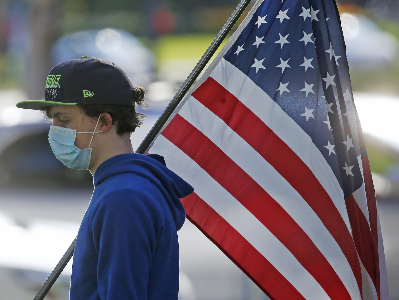 Muž v rúšku nesie americkú vlajku ulicami Salt Lake City