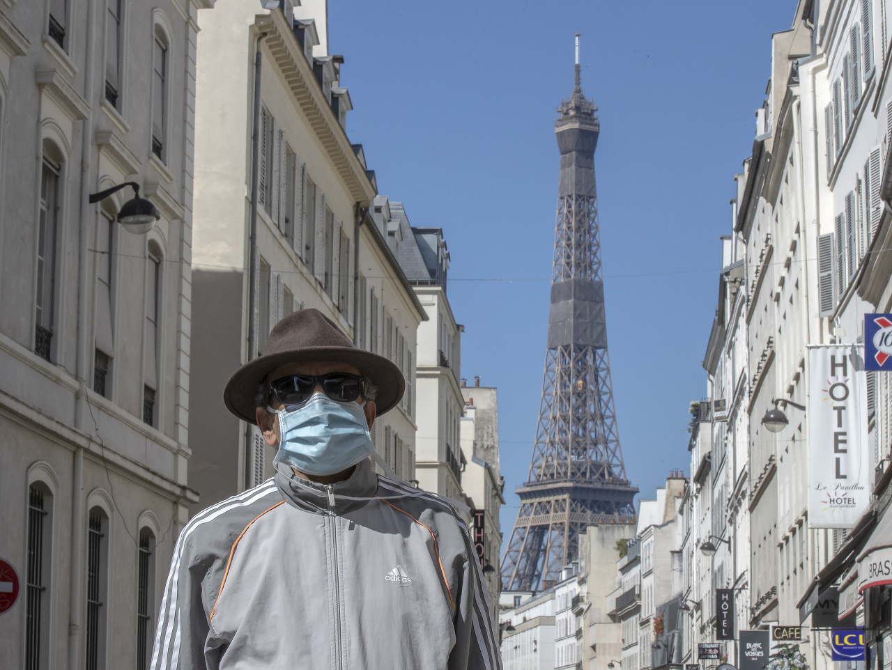Muž chrániaci sa rúškom pred Eiffelovou vežou v Paríži.