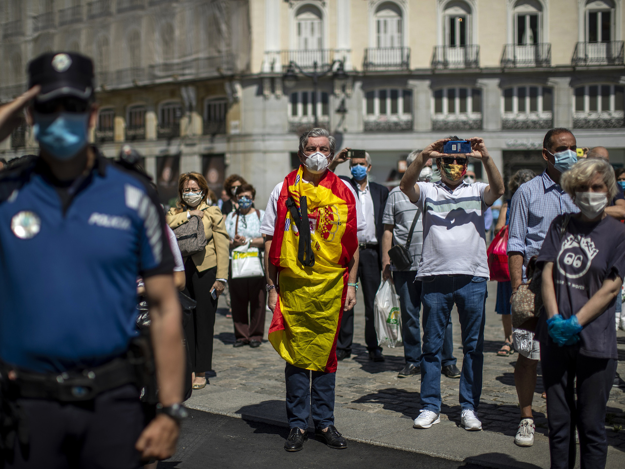 Ľudia stoja počas minúty ticha, ktorou si na pravé poludnie uctili obete ochorenia COVID-19 v centre Madridu