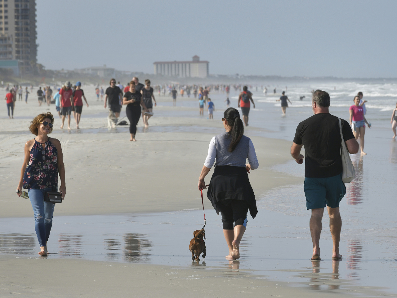 Ľudia kráčajú na pláži počas pandémie nového koronavírusu v Jacksonville Beach na Floride.