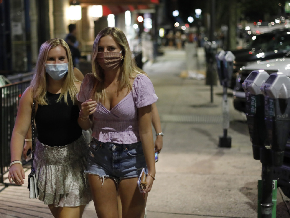  Ženy s ochrannými rúškami na zabránenie šírenia nového koronavírusu kráčajú po ulici v centre Atén.