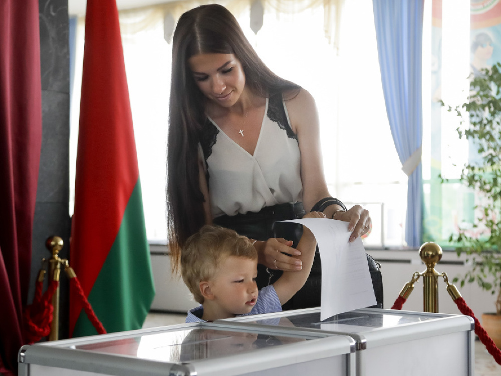 Bieloruská volička s dieťaťom hádže do urny svoj hlas počas hlasovania v prezidentských voľbách vo volebnej miestnosti v Minsku.