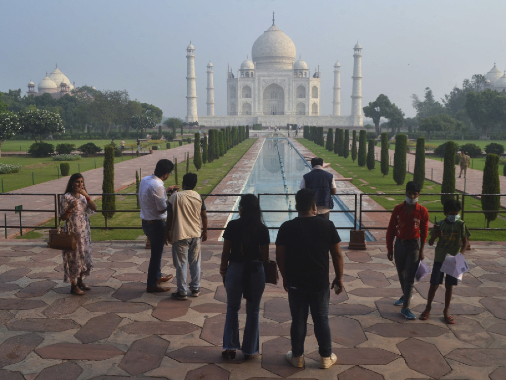 Malá skupina indických turistov stojí pred pamätníkom Tádž Mahal v meste Ágra.