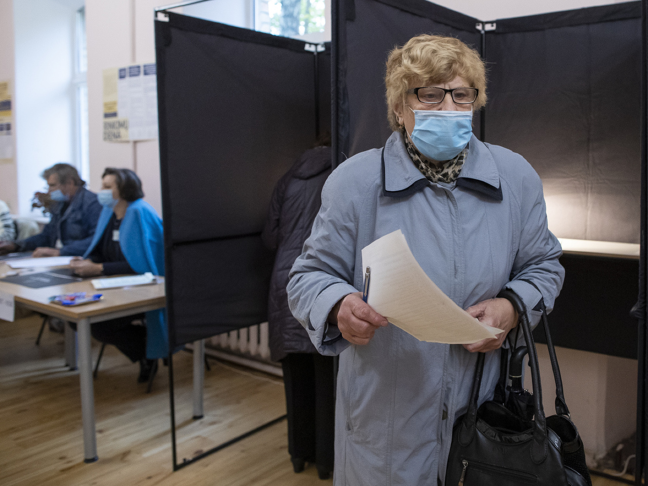  Na snímke volička s ochranným rúškom hlasuje počas 1. kola parlamentných volieb vo Vilniuse.