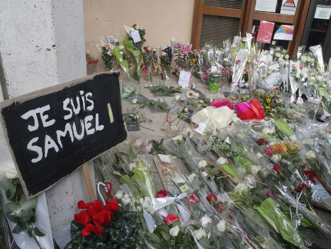 Nápis Som Samuel a kvety sú pred budovou strednej školy, pred ktorou útočník zabil učiteľa dejepisu Samuela Patyho vo francúzskom meste Conflans-Sainte-Honorine