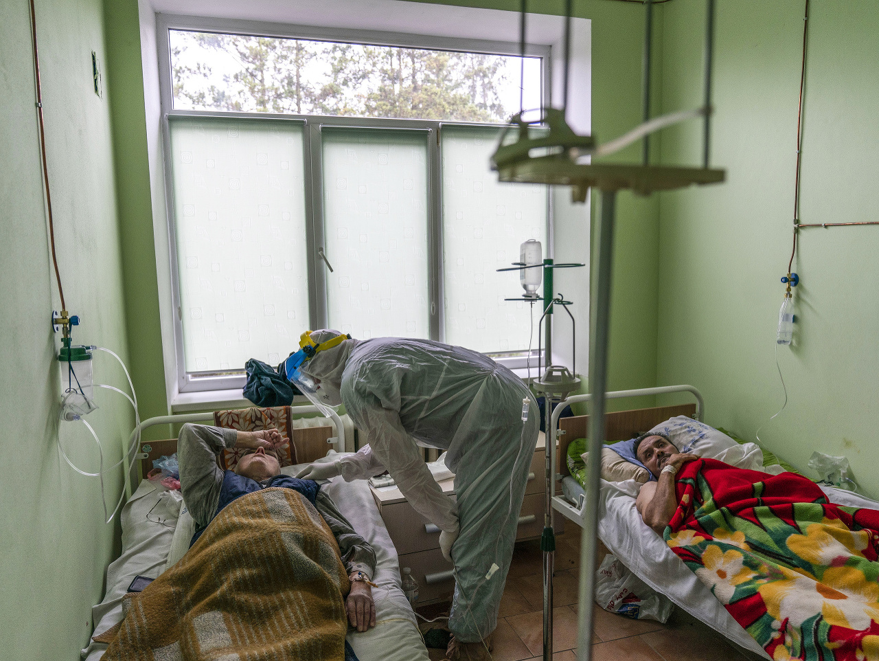 Lekár v špeciálnom ochrannom odeve  sa rozpráva s pacientom infikovaným novým typom koronavírusu na Ukrajine