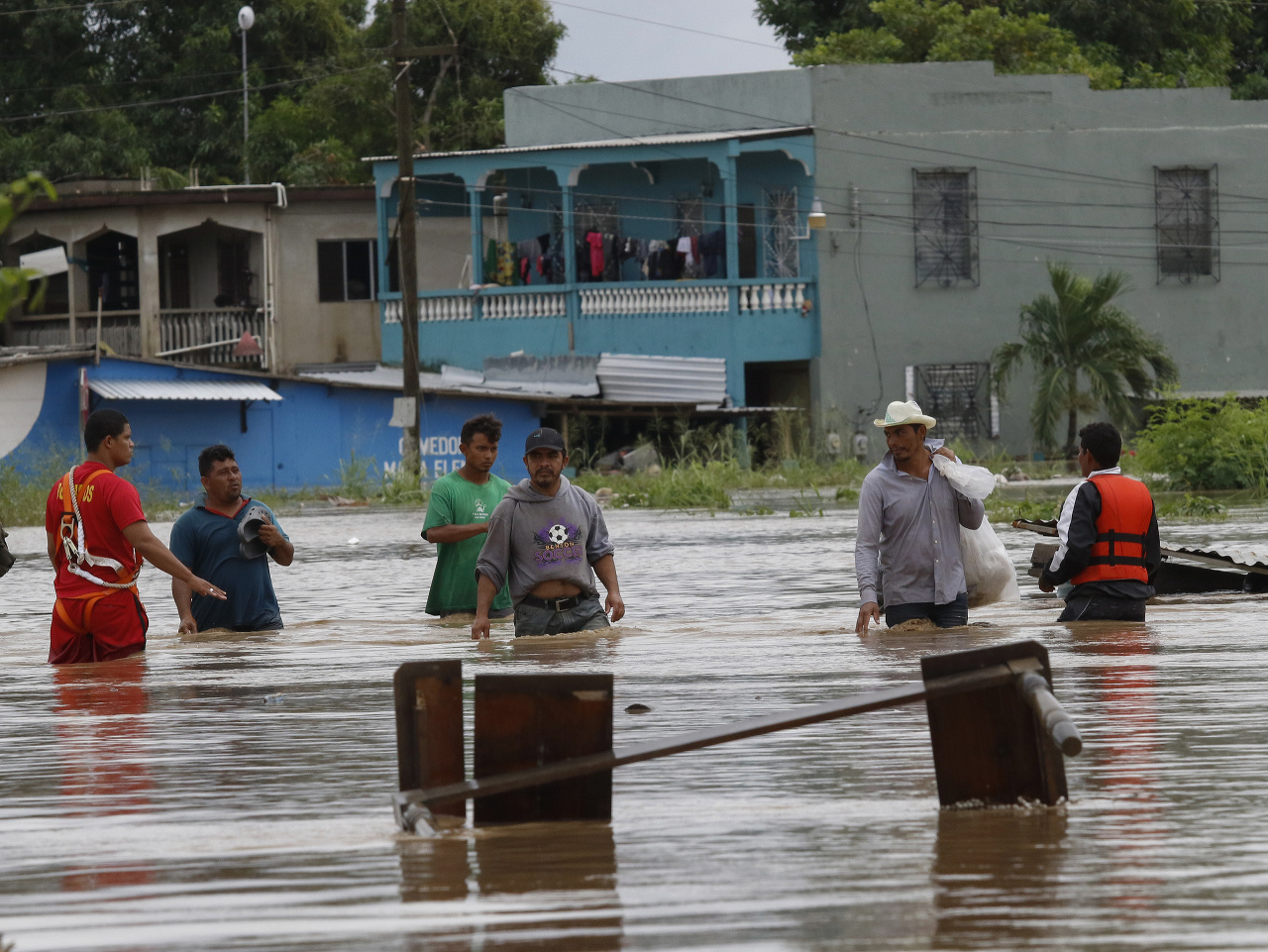 Muži sa brodia po zaplavenej cesta po vyčíňaní hurikánu Iota v honduraskom meste La Lima