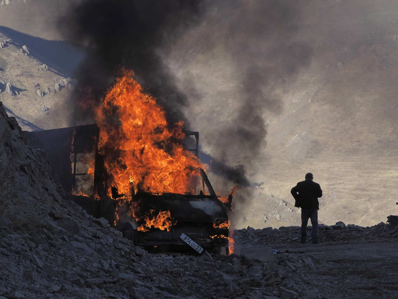 Na snímke muž stojí pri horiacom aute vedľa cesty vedúcej na horský priechod neďaleko hranice medzi Náhorným Karabachom a Arménskom počas bojov medzi arménskymi a azerbajdžanskými vojenskými jednotkami v samozvanom regióne Náhorný Karabach 8. novembra 202