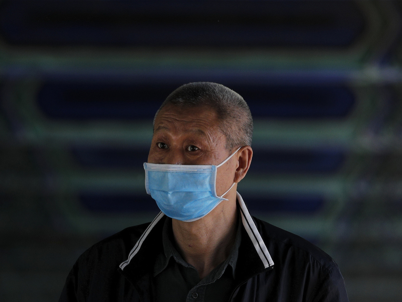 Muž v Číne chrániaci sa rúškom