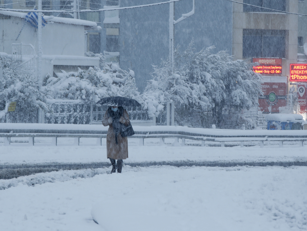 Na snímke žena kráča v hustom snežení v Aténach