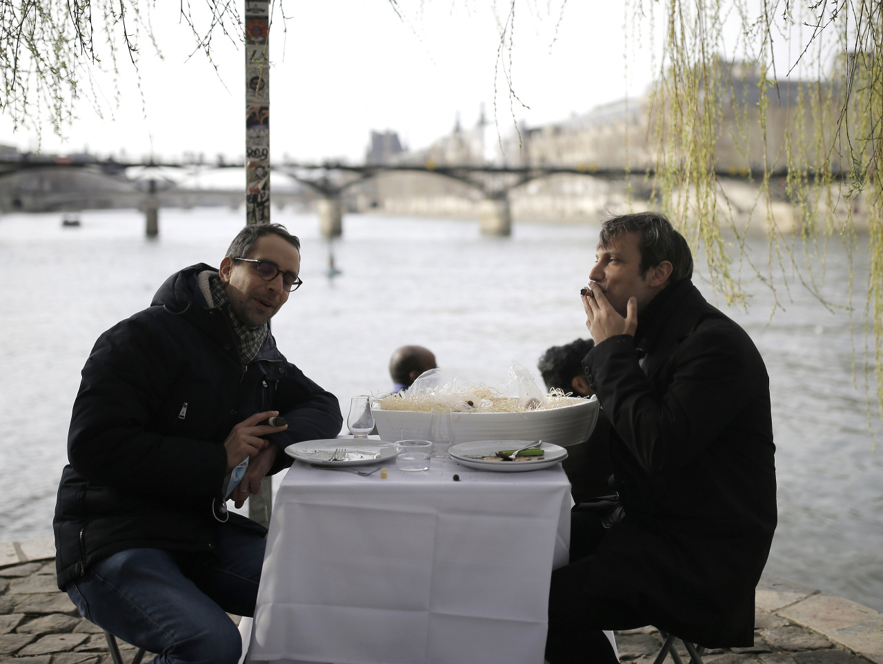 Emmanuel (vľavo) a Martin fajčia cigaru počas improvizovaného obeda na brehu rieky Seina v Paríži