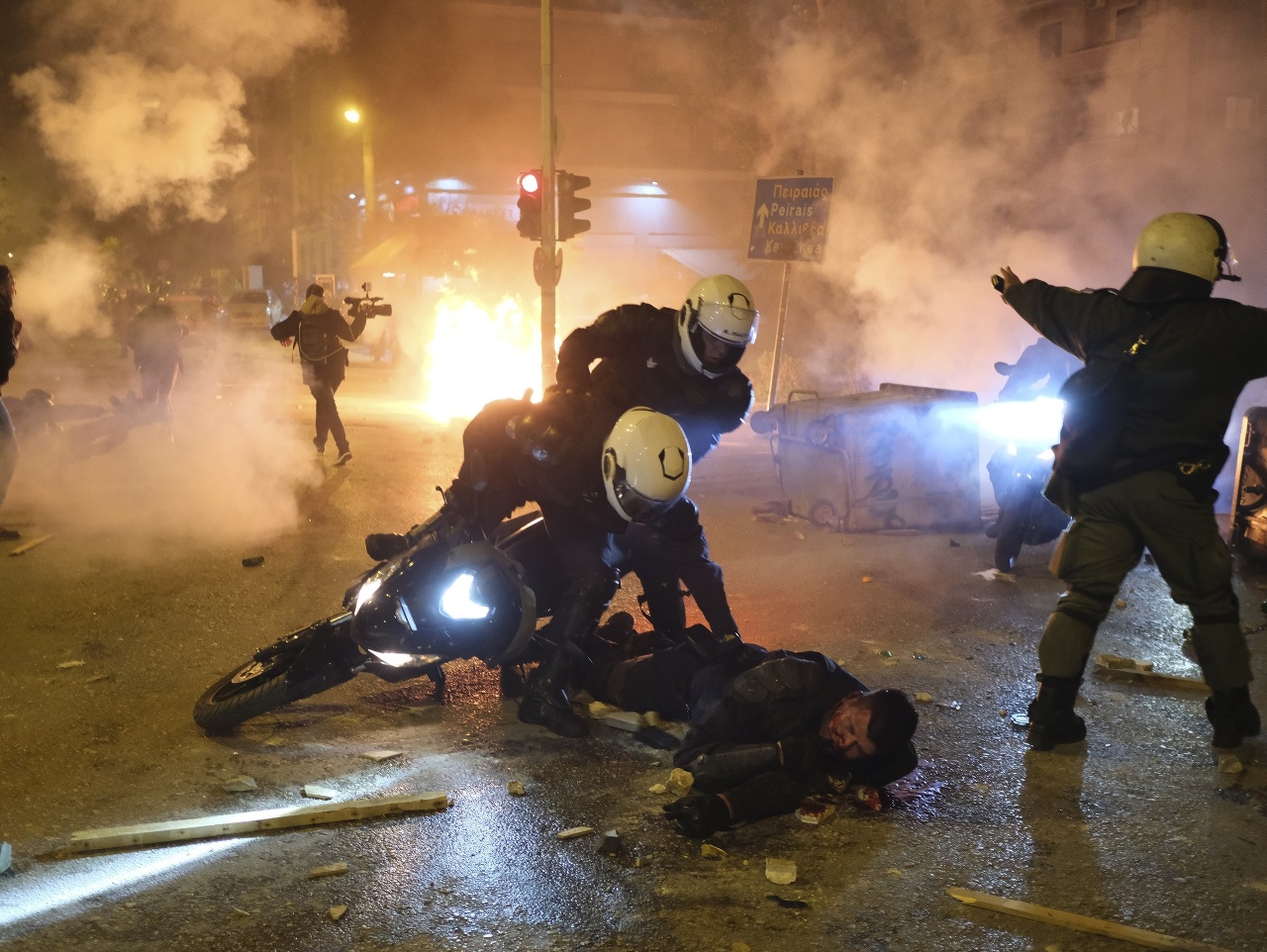 Policajt leží na zemi zranený počas potýčky v Aténachc