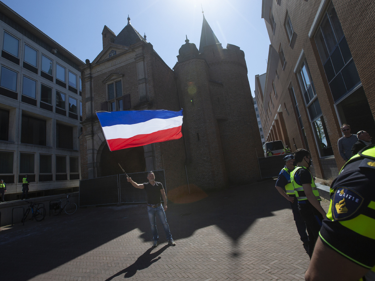 Muž veje pred políciou s holandskou vlajkou na protest proti opatreniam