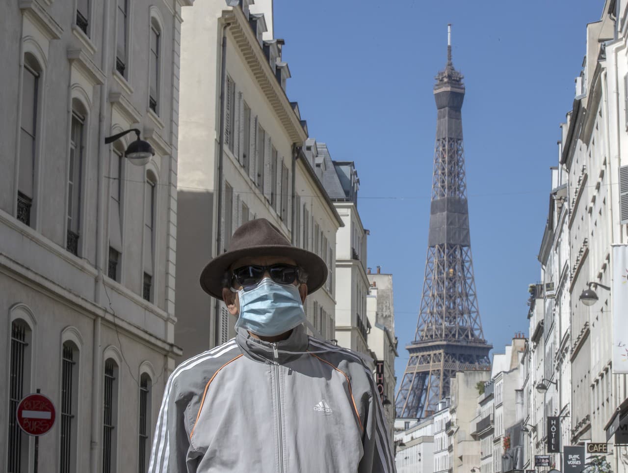 Muž chrániaci sa rúškom pred Eiffelovou vežou v Paríži
