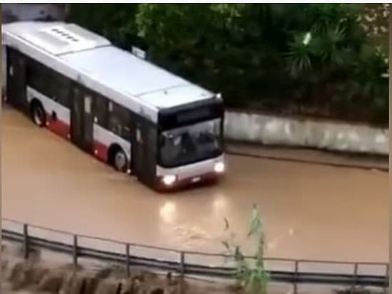 Autobus odnáša prúd vody zo záplav.
