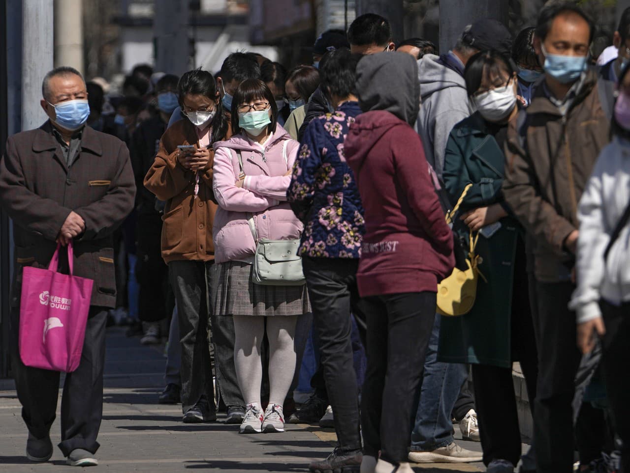Obyvatelia čakajú v rade počas testovania na ochorenie COVID-19 na testovacom mieste neďaleko obytných domov v Pekingu