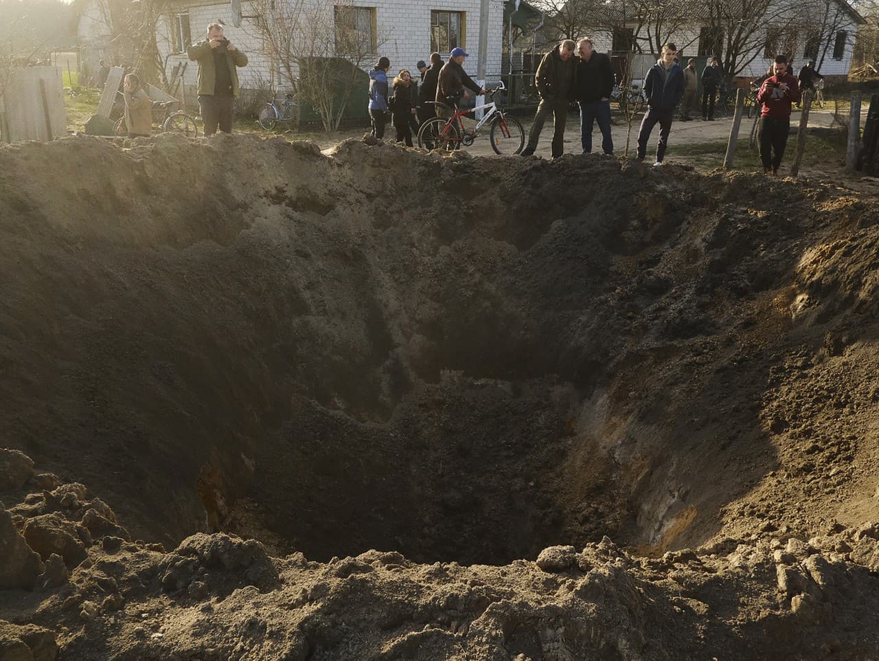 Ľudia sa pozerajú na kráter po výbuchu v dedine Horodnya