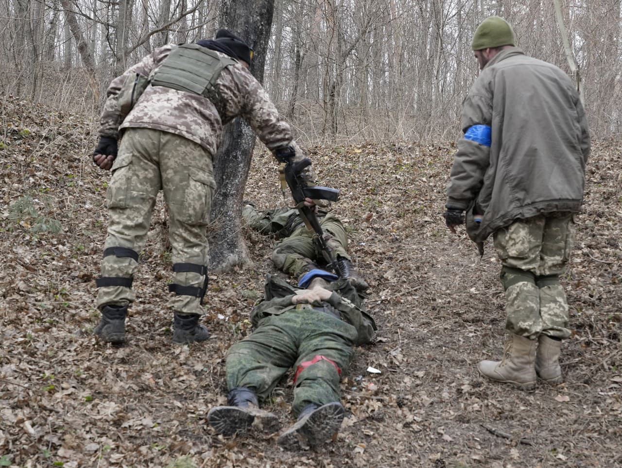 Ukrajinskí vojaci si prezerajú telá mŕtvych ruských vojakov