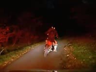 Českí policajti prenasledujú motorkára po lesnej ceste.