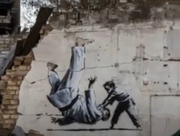 Maľba od Banksyho na stene obytnej budovy.