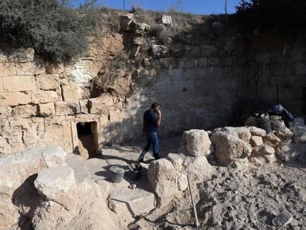 Archeológ stojí pred vchodom do jaskyne