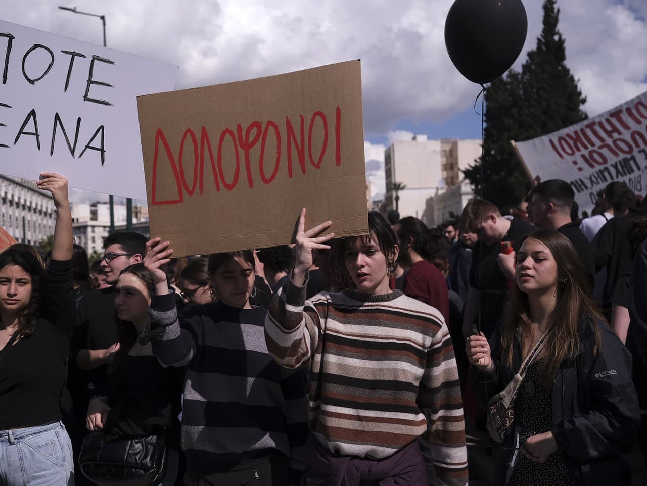 Ľudia držia transparenty s nápismi „Vrahovia“, v strede a „Už nikdy viac“, počas protestu pred gréckym parlamentom v Aténach v Grécku, v nedeľu 5. marca 2023.