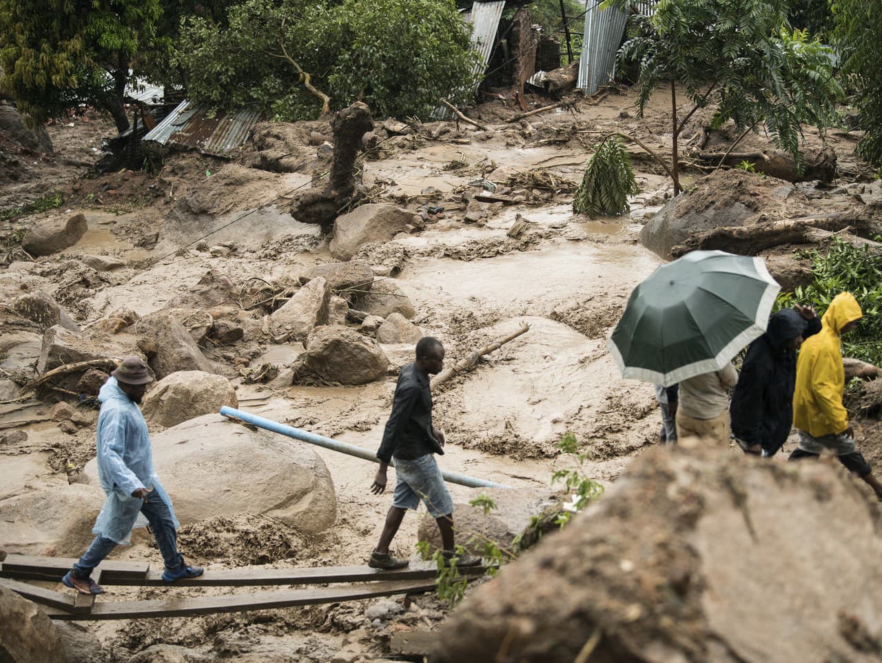 Ľudia kráčajú cez rozvodnenú rieku po vyčíňaní cyklóny Freddy