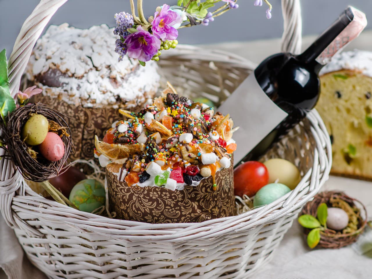 Veľkonočný košík s veľkonočným koláčom, vínom a kraslicami.