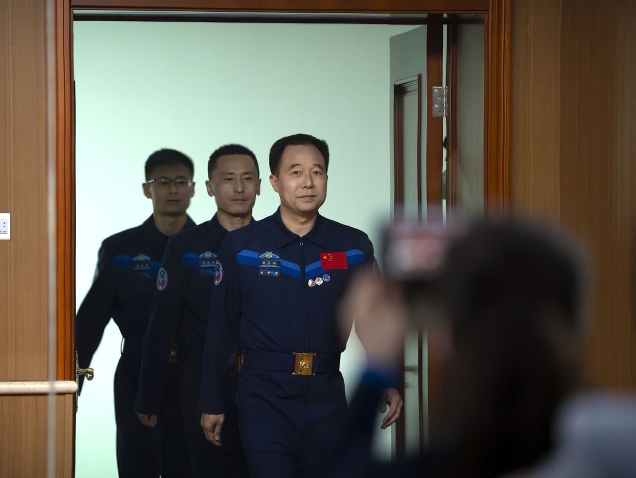 Čínski astronauti z misie Šen-čou-16, Jing Haipeng, Zhu Yangzhu a Gui Haichao, prichádzajú na stretnutie tlače v stredisku štartu satelitu Jiuquan na severozápade Číny.