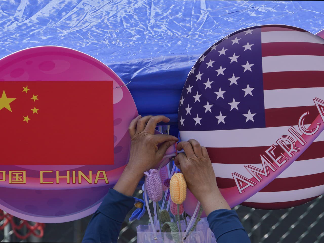 Predavač oblieka kvety medzi planétami v tvare čínskej a americkej vlajky, ktoré sú vystavené v obchode počas jarného karnevalu v Pekingu 13. mája 2023.  Vysokopostavení americkí a čínski diplomati viedli v Pekingu 