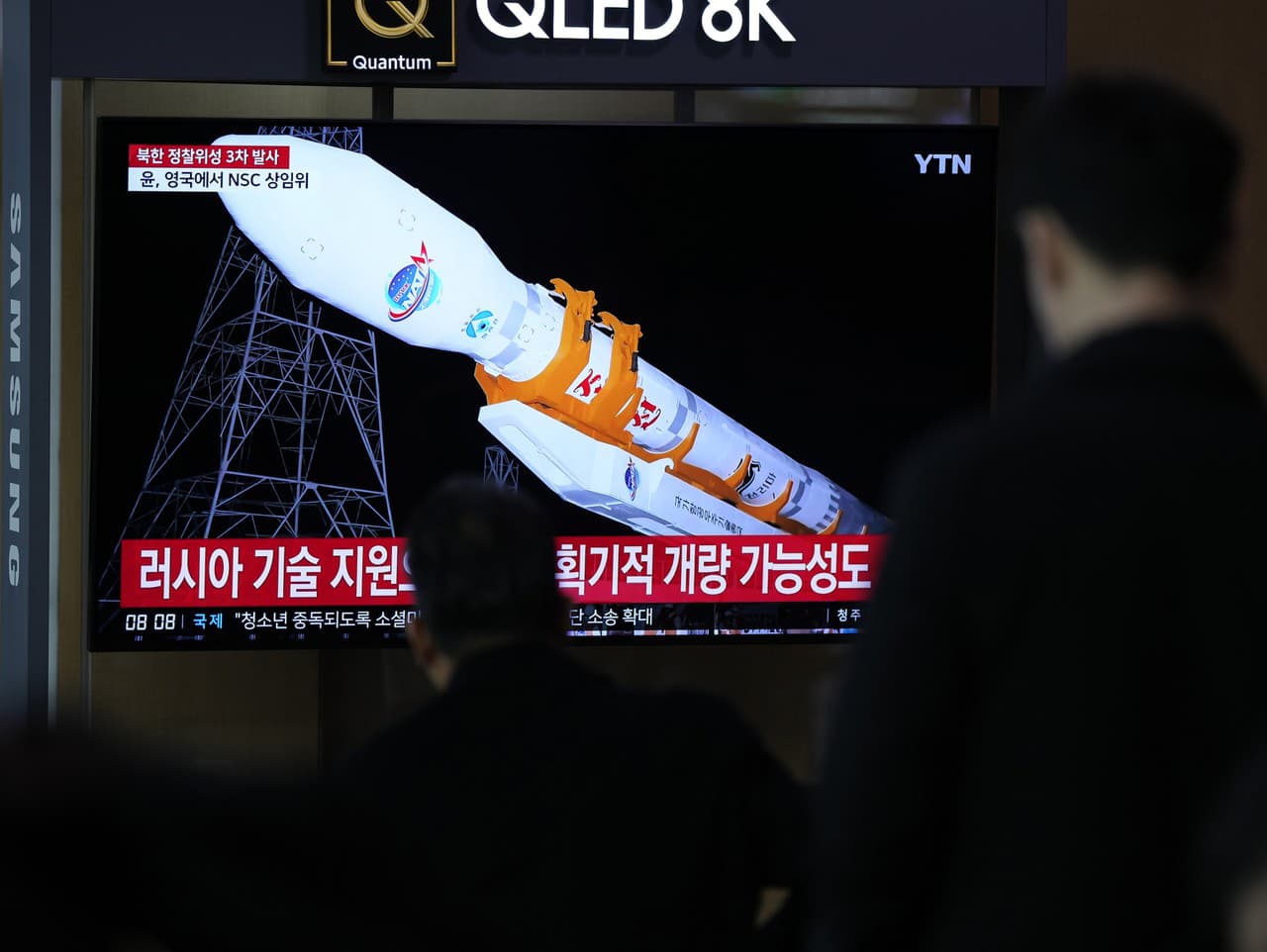 Na televíznej obrazovke sa zobrazuje správa o tom, že Severná Kórea vypustila špionážny satelit na obežnú dráhu pri svojom treťom pokuse o vypustenie v tomto roku počas spravodajského programu na železničnej stanici v Soule v Južnej Kórei v stredu 22. nov