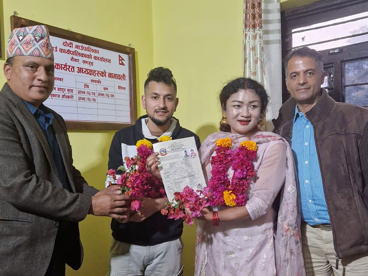 Pár rovnakého pohlavia Surendra Pandey, druhý vľavo, a Maya Gurung, ktorá sa zosobášili pred šiestimi rokmi, pózujú na fotografii s osvedčením o registrácii manželstva na úrade rady obce Dorje.