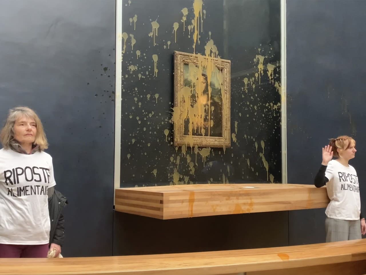 Aktivistky gestikulujú po tom, čo hodili polievku na sklo chrániace Monu Lisu v múzeu Louvre