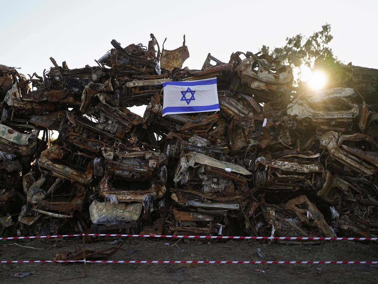 Izraelská vlajka je položená na hromade ohorených vozidiel, ktoré zhoreli pri krvavom cezhraničnom útoku militantov Hamasu 7. októbra pri meste Netivot na juhu Izraela v nedeľu 7. januára 2024.