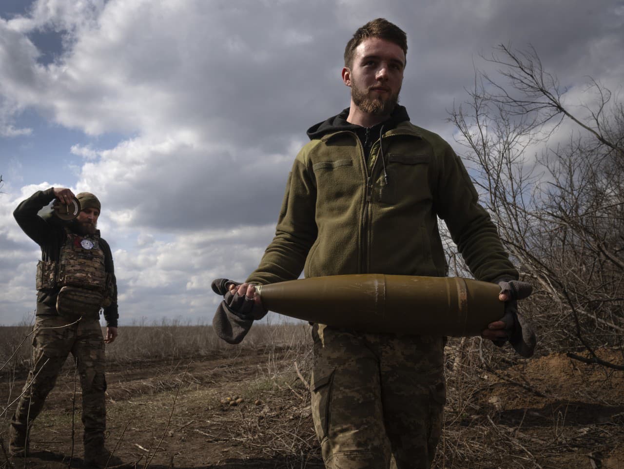 Ukrajinský vojak nesie na fronte delostreleckú muníciu 