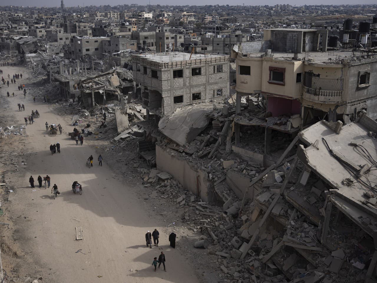 Palestínčania prechádzajú zničenými budovami po izraelskej leteckej a pozemnej ofenzíve v Chán Júnis na juhu pásma Gazy
