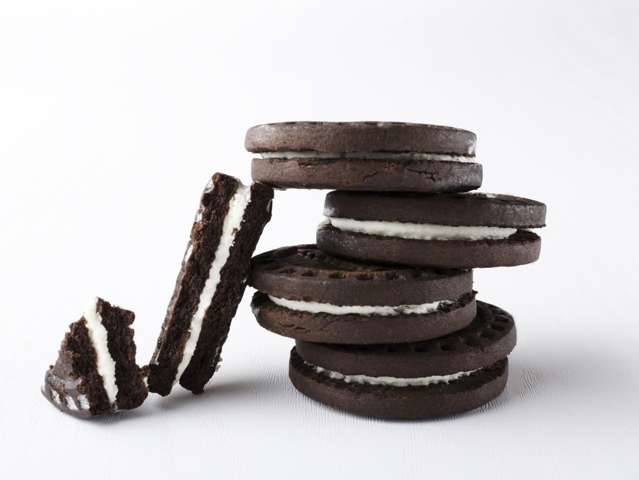 Closeup of stack of dark sandwich cookies and broken on the white background.Vertical image