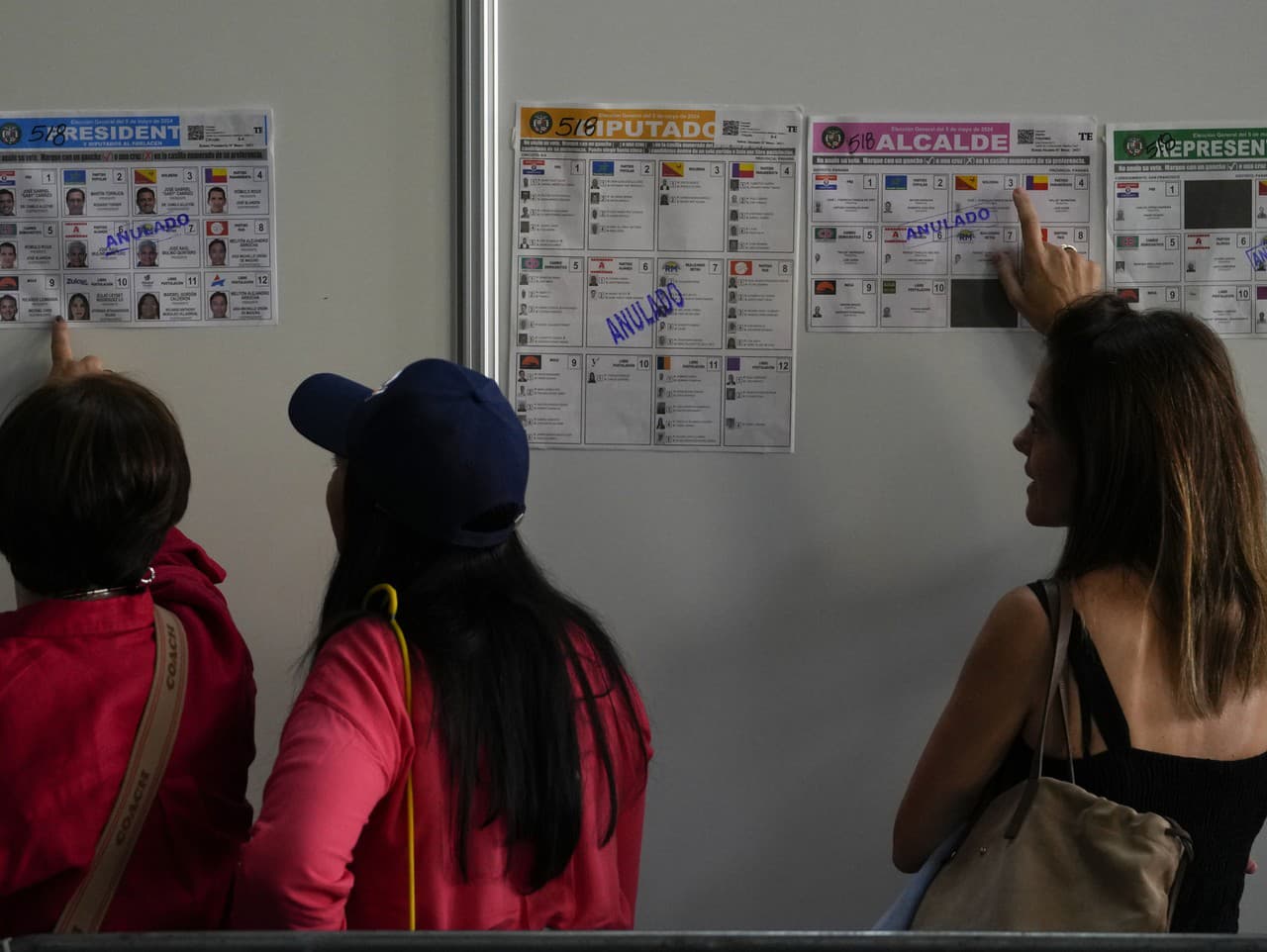 Voličky kontrolujú vzory hlasovacích lístkov na stene volebnej miestnosti  počas parlamentných  a prezidentských volieb v Paname