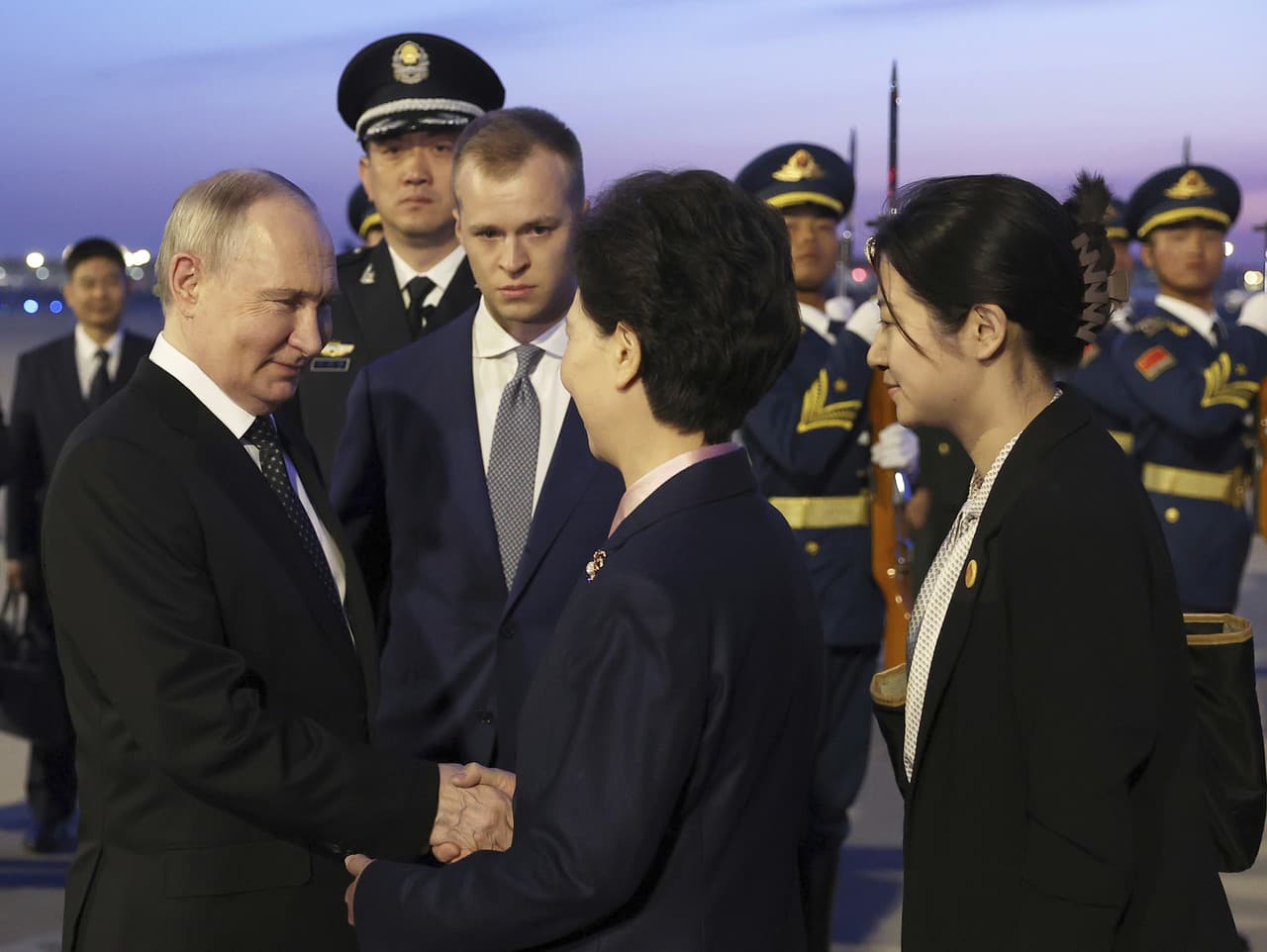 Ruský prezident Vladimir Putin (vľavo) si podáva ruku s čínskym štátnym radcom Šen I-čchinom (druhý sprava) po prílete na medzinárodné letisko v Pekingu vo štvrtok 16. mája 2024. 