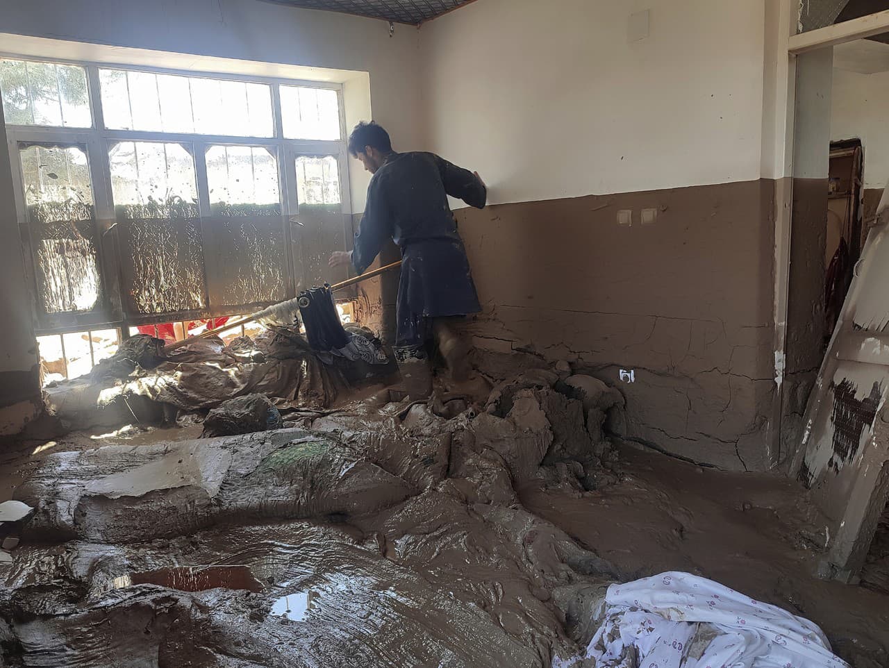 Muž zbiera svoje veci z poškodeného domu po silných záplavách v provincii Baglán na severe Afganistanu