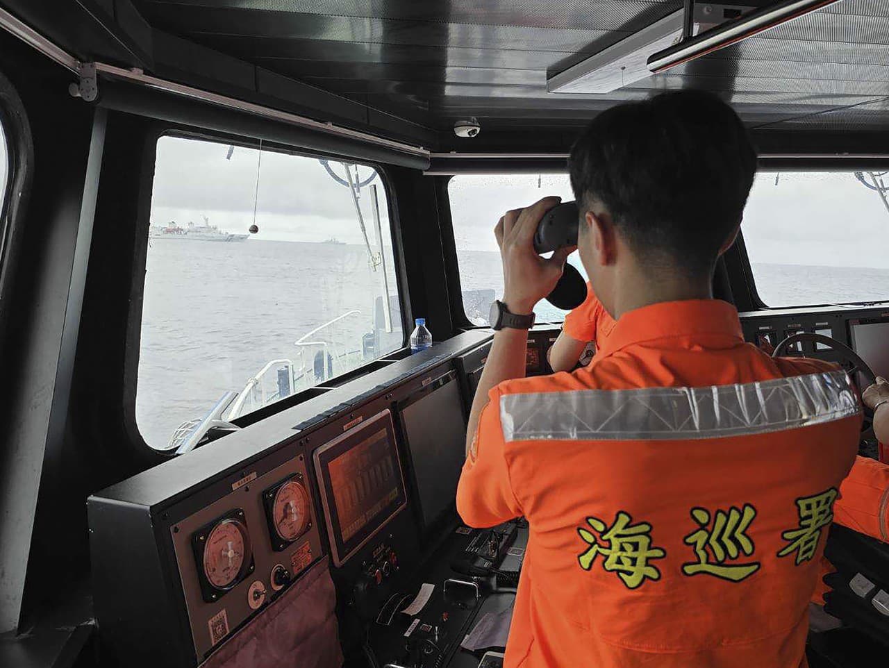 Na snímke, ktorú zverejnila taiwanská pobrežná stráž, jej člen monitoruje plavidlo čínskeho námorníctva, ktoré operuje v blízkosti ostrovčeka Pengjia severne od Taiwanu vo štvrtok 23. mája 2024.