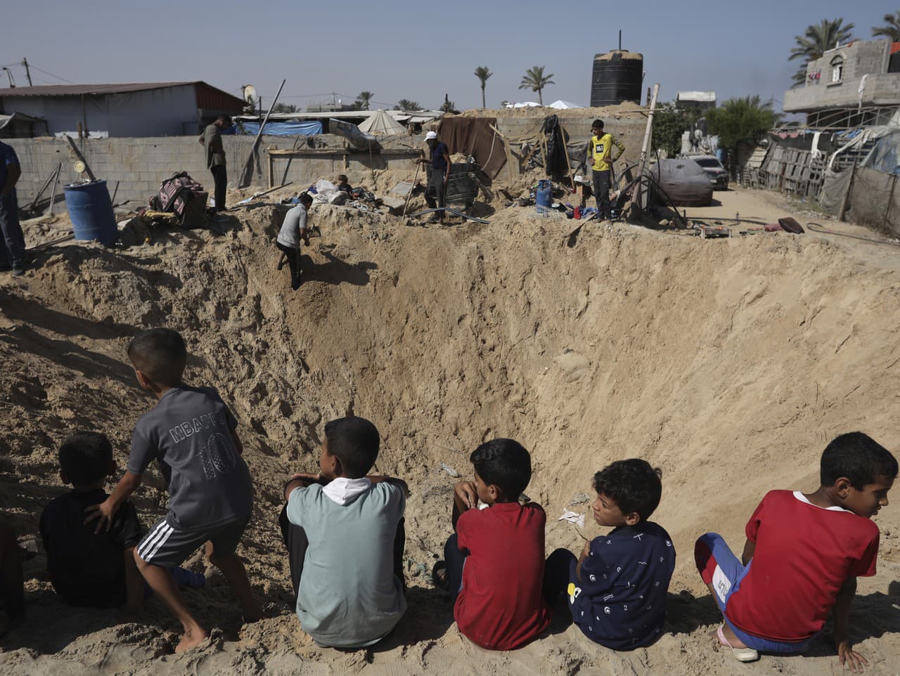 Palestínske deti sedia na okraji krátera po izraelskom leteckom útoku v Chán Júnise na juhu pásma Gazy v piatok 21. júna 2024.