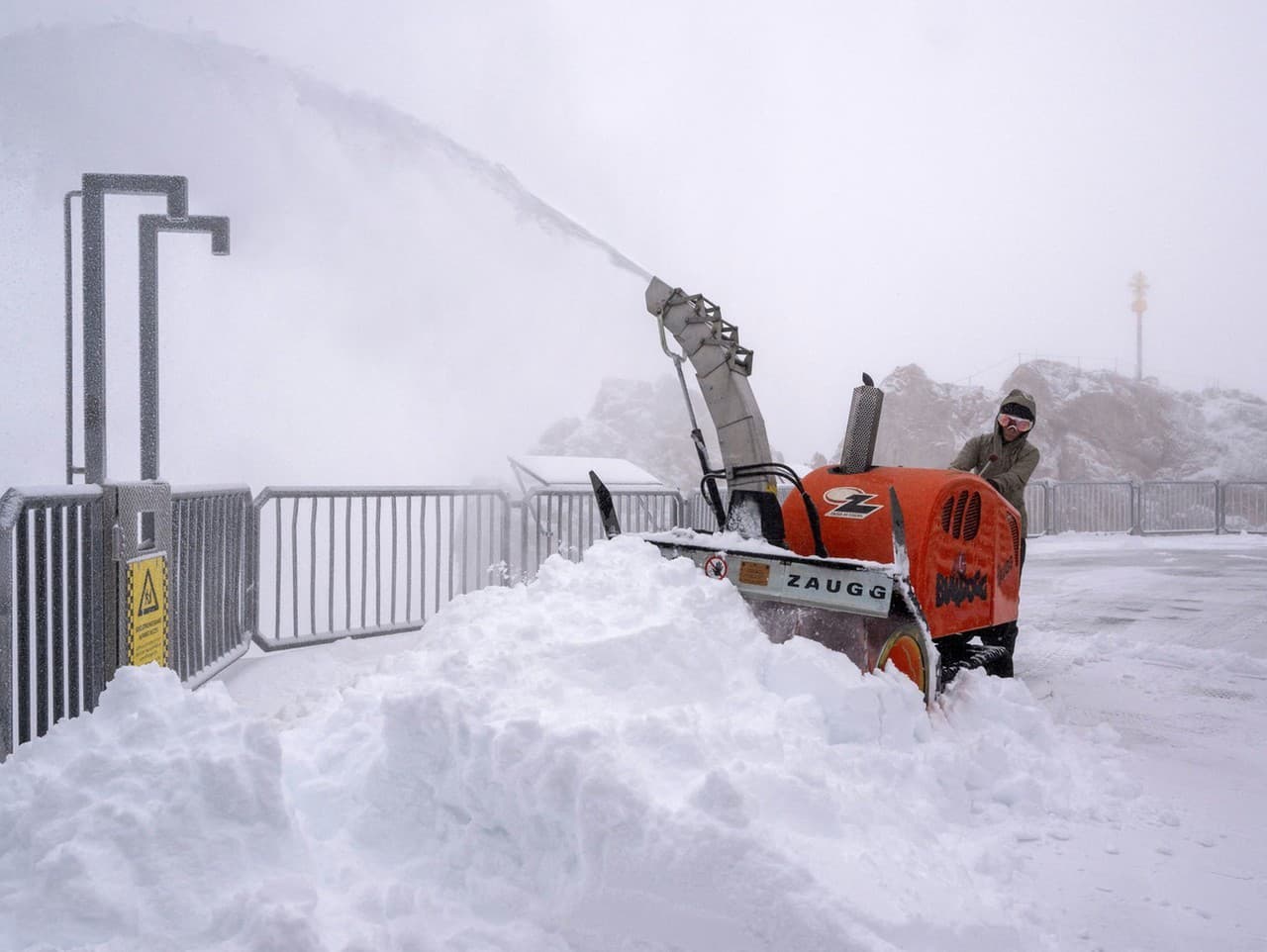 Žena odpratáva čerstvý sneh na vyhliadkovej plošine na Zugspitze.