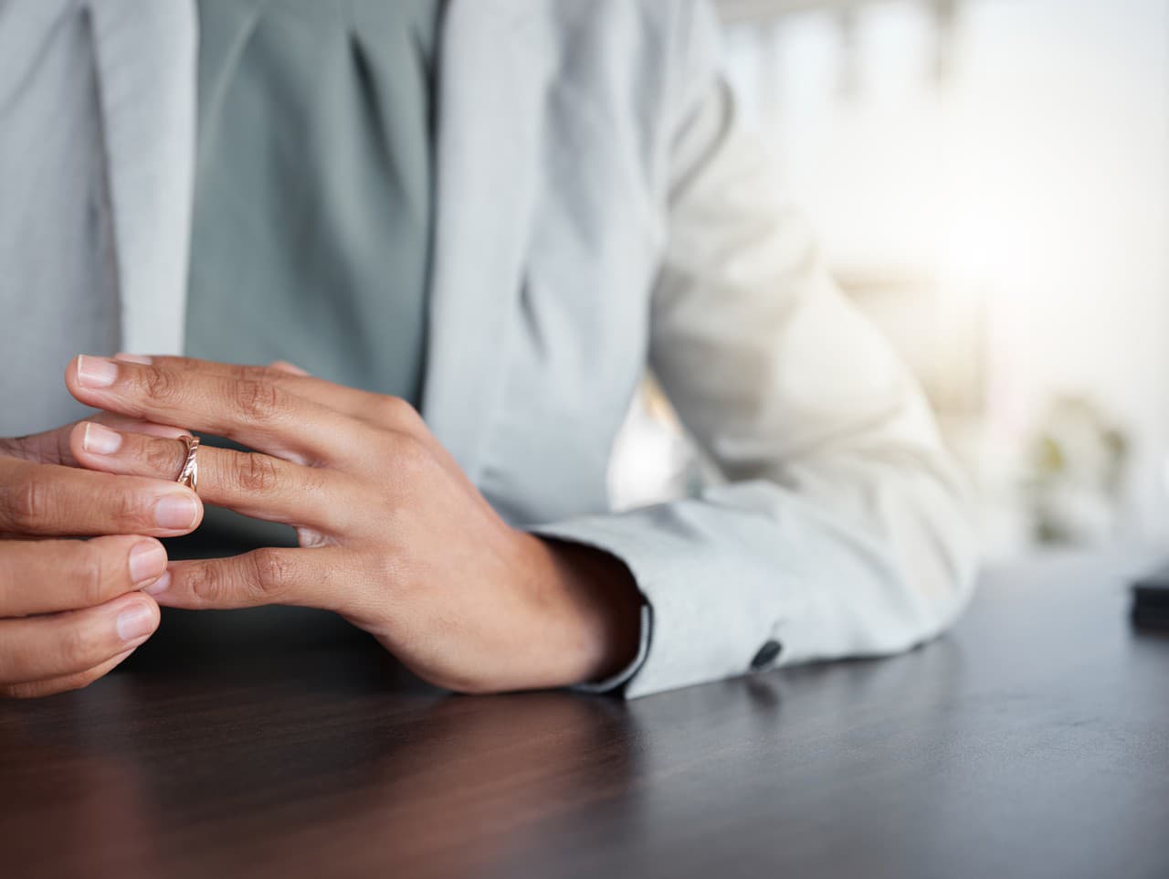 Hand or finger, ring and divorce of a woman at table with doubt, anxiety or thinking about depression. Female person taking off wedding band jewellery for separation counselling, cheating or mistake