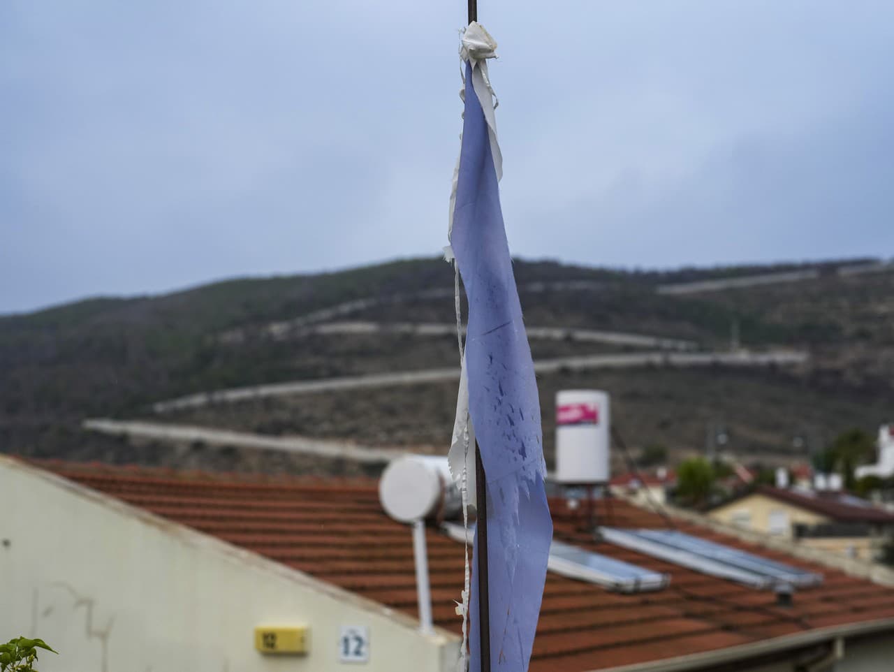 Izraelská vlajka visí pri vchode do domu neďaleko izraelsko-libanonskej hranice v pozadí v meste Šlomí na severe Izraela v stredu 27. novembra 2024.