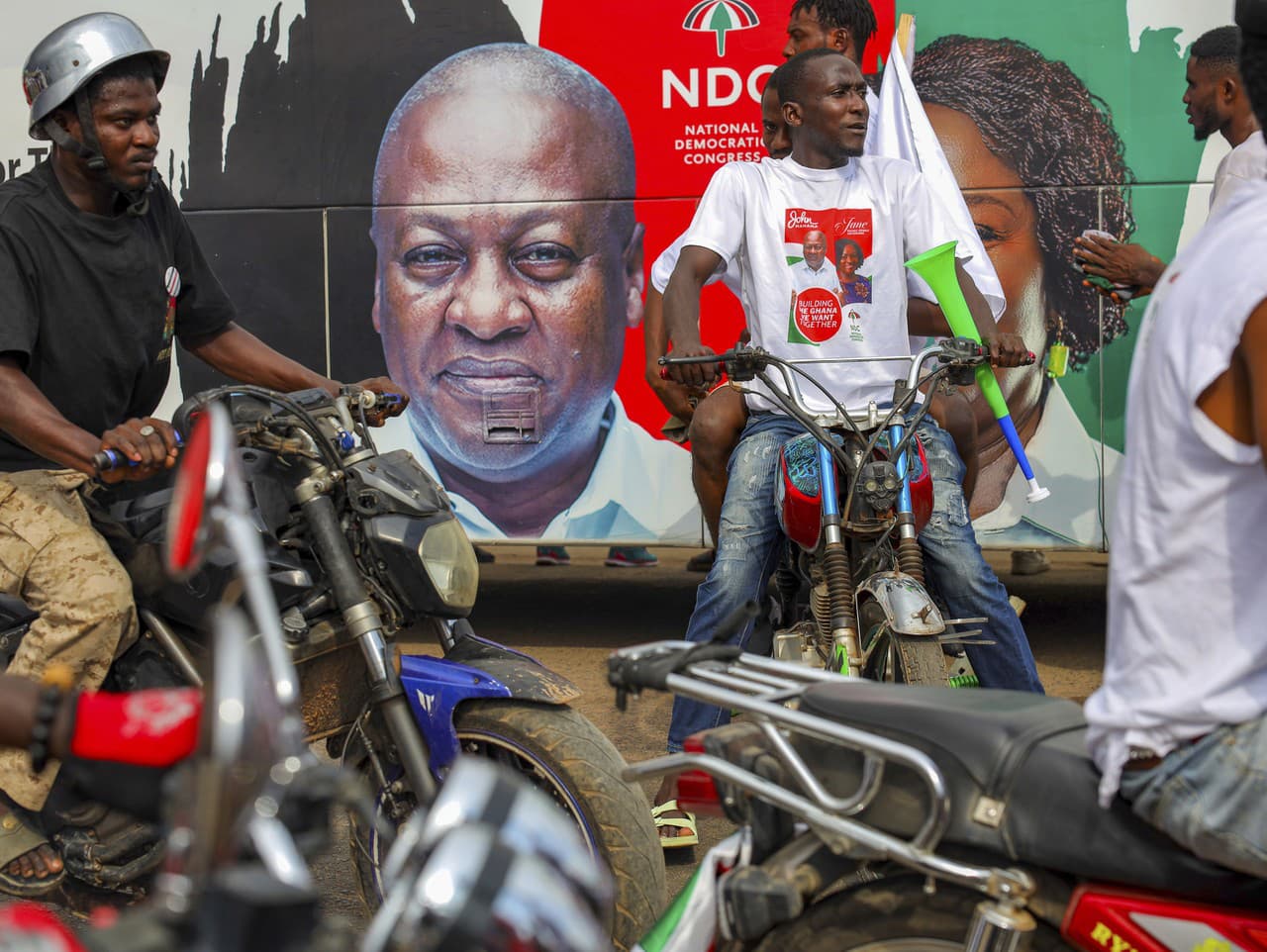 Na billboarde je vyobrazený John Mahama a okolo jazdia na motorkách jeho priaznivci